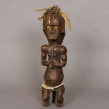 An African tribal carved wooden figure Modelled seated, hands clasped and with beadwork belt,