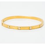 An 18 ct gold Cartier style bangle Of hinged form. 6.75 cm wide.