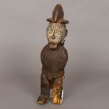 An African carved wooden tribal figure Modelled standing armless wearing a headdress and with