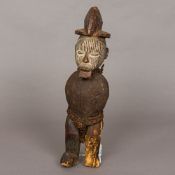 An African carved wooden tribal figure Modelled standing armless wearing a headdress and with