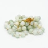A celadon jade bead necklace Set with a gilt metal filigree clasp. 67 cm long.