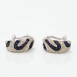 A pair of 18 ct white gold diamond and sapphire earrings Each with scrolling banded decoration.