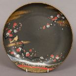 A 20th century Japanese porcelain dish Decorated with a bird on a blossoming branch on a black