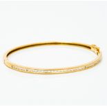 An 18 ct gold and diamond bangle Of hinged form, one side channel set with diamonds. 6.5 cm wide.