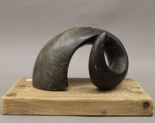 A ram's horn mounted on a wooden plinth. 27.5 cm wide.