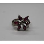 A gold ruby and diamond flowerhead ring. Ring size M (5.1 grammes total weight).