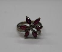 A gold ruby and diamond flowerhead ring. Ring size M (5.1 grammes total weight).