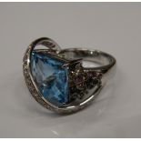 An 18 K white gold and blue topaz ring, set with diamonds and multi gem floral decoration.