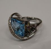 An 18 K white gold and blue topaz ring, set with diamonds and multi gem floral decoration.