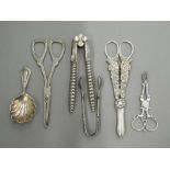 A quantity of various tongs, a caddy spoon, etc., including silver. Largest tongs 16.5 cm long.
