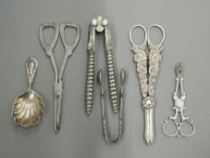 A quantity of various tongs, a caddy spoon, etc., including silver. Largest tongs 16.5 cm long.