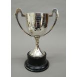 A silver twin handled trophy mounted on a turned plinth base.
