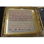 A framed sampler by Eliza M Thurkettle, aged 11, dated 1887. 46 x 42 cm overall.