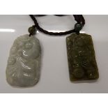 Two boxed jade pendants. Each approximately 4 cm high.