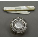 A silver pill box, together with a silver and mother-of-pearl penknife. Pill box 3.25 cm diameter.