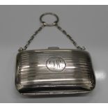 A silver purse with finger ring and chain, with fitted interior. 8 cm wide (67.
