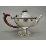 A silver teapot. 15 cm high; 21 cm wide (10.