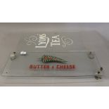 A vintage glass advertising panel for New Zealand Butter and Cheese and a glass panel with Lyons