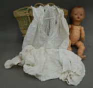 An early 20th century doll and two lace gowns. Doll approximately 49 cm high.