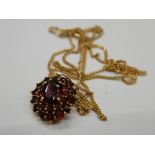 A 9 ct gold and garnet pendant on a 9 ct gold chain. Pendant 1.75 cm high (4.