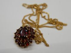 A 9 ct gold and garnet pendant on a 9 ct gold chain. Pendant 1.75 cm high (4.
