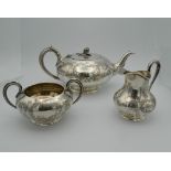 A Victorian silver three piece chased tea set. The tea pot 27 cm long (34.