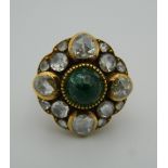 An unmarked 18 ct gold diamond and emerald ring. 2 cm diameter. Ring size I/J.