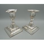 A pair of silver square based candlesticks, hallmarked Sheffield 1895. 12 cm high.