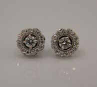 A pair of 18 ct white gold diamond halo earrings.