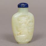 A small Chinese carved jade snuff bottle Of flattened form, with lapis lazuli stopper,