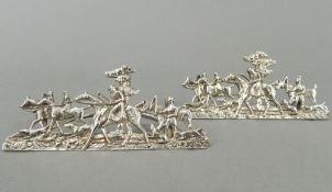 A pair of silver menu holders depicting hunting scenes. 8.5 cm long, 3.5 cm high. (34.