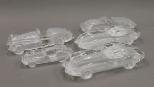 Five glass models of vintage cars, including E-Type Jaguar. The largest 18 cm long.