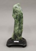 A Chinese green jade scholars rock, fitted to later base. 34 cm high overall.