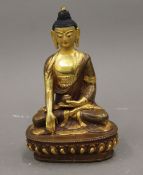 A seated part gilded copper buddha with a finely painted face. 16 cm high.
