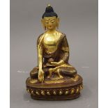 A seated part gilded copper buddha with a finely painted face. 16 cm high.