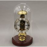 A brass skeleton clock, under a glass dome. 29 cm high.