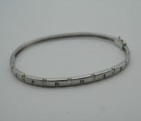 A 9 ct white gold bangle set with diamonds. 6.5 cm wide (9.