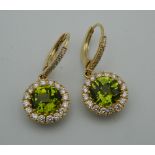 A pair of 18 ct gold peridot and diamond drop earrings. Each 1.2 cm diameter.