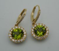 A pair of 18 ct gold peridot and diamond drop earrings. Each 1.2 cm diameter.