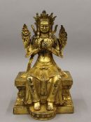 A gilt bronze figure of a deity sitting on a throne. 22 cm high.