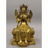 A gilt bronze figure of a deity sitting on a throne. 22 cm high.
