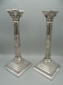 A pair of hallmarked English silver Corinthian column candlesticks. One sconce lacking. 31 cm high.