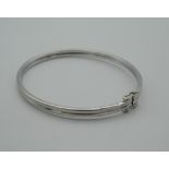A 9 ct white gold bangle, housed in a velvet pouch. 6.5 cm wide (5.