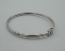 A 9 ct white gold bangle, housed in a velvet pouch. 6.5 cm wide (5.