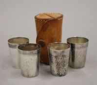 A set of four cased silver shot cups. The case 8 cm high.