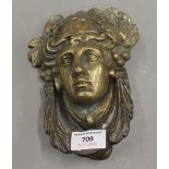 A large vintage brass door knocker depicting a classical male face adorned with grapes and vine