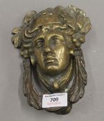 A large vintage brass door knocker depicting a classical male face adorned with grapes and vine