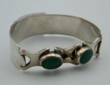 A silver bangle set with malachite. 6 cm wide.