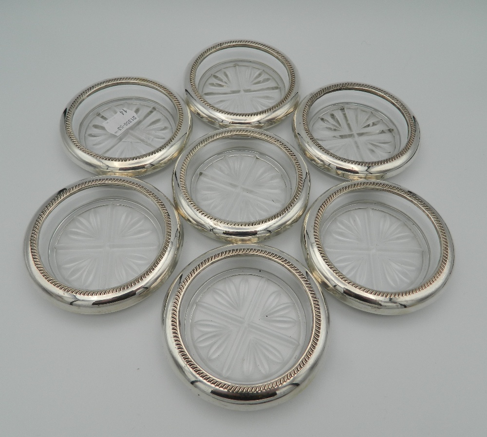 Seven glass and sterling silver rimmed coasters, stamped sterling. Each 9.5 cm diameter.