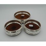 A trio of silver and wood coasters,